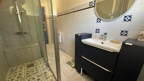 Ein Badezimmer mit Dusche, Waschbecken und Spiegel.