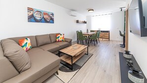 A modern living room with a sofa, coffee table, and dining area.