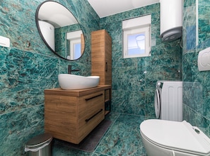 Un baño moderno con un lavamanos blanco tipo recipiente, tocador de madera, un espejo, una ventana y un inodoro.