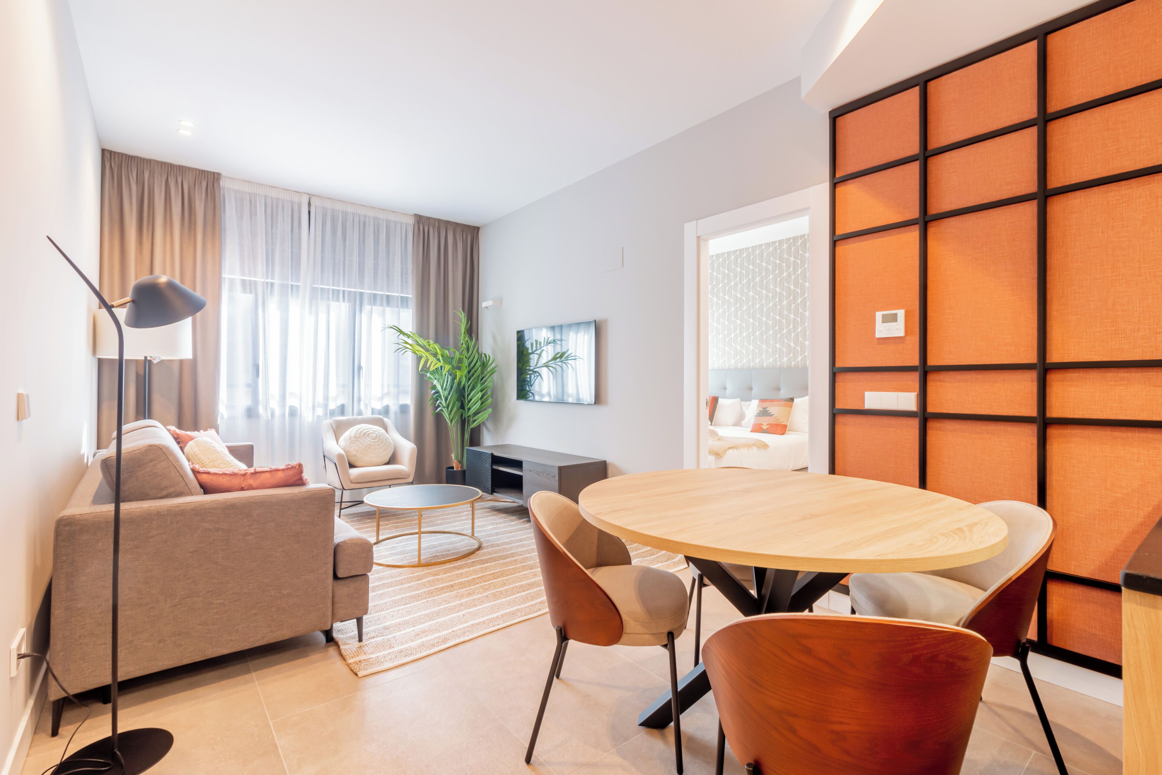 A modern living room with a sofa, a round wooden table, and chairs.