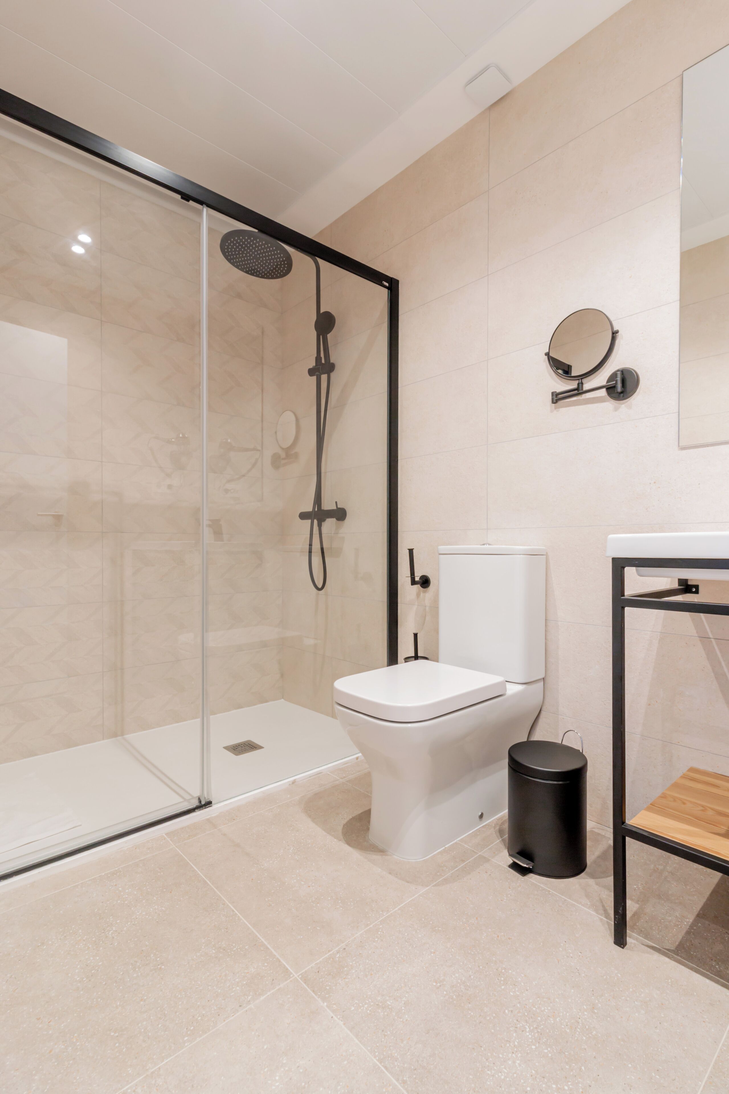 A modern bathroom with a glass-enclosed shower, a white toilet, and a sink with a mirror.