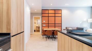 A modern kitchen with wooden cabinets, a black countertop, and a dining area with a table and chairs.