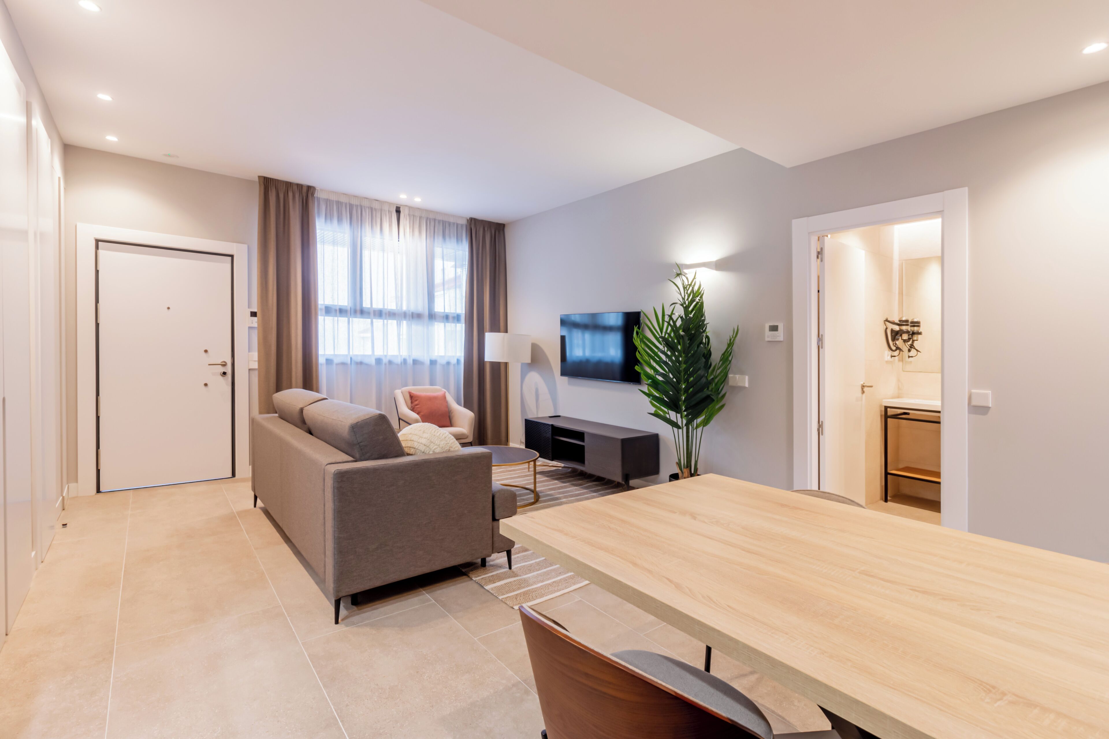 A modern living room with a sofa, a coffee table, a TV, and a dining table.