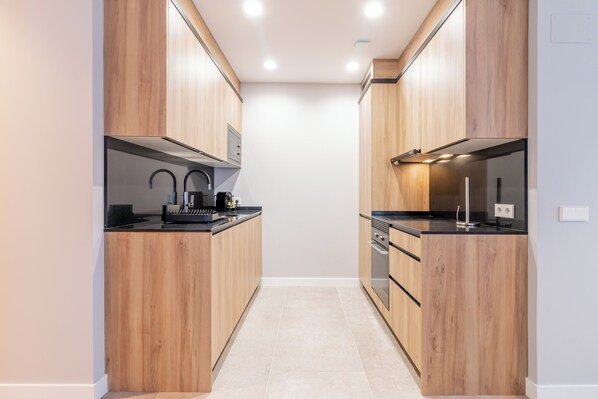 A modern kitchen with wooden cabinets, stainless steel appliances, and a black countertop.