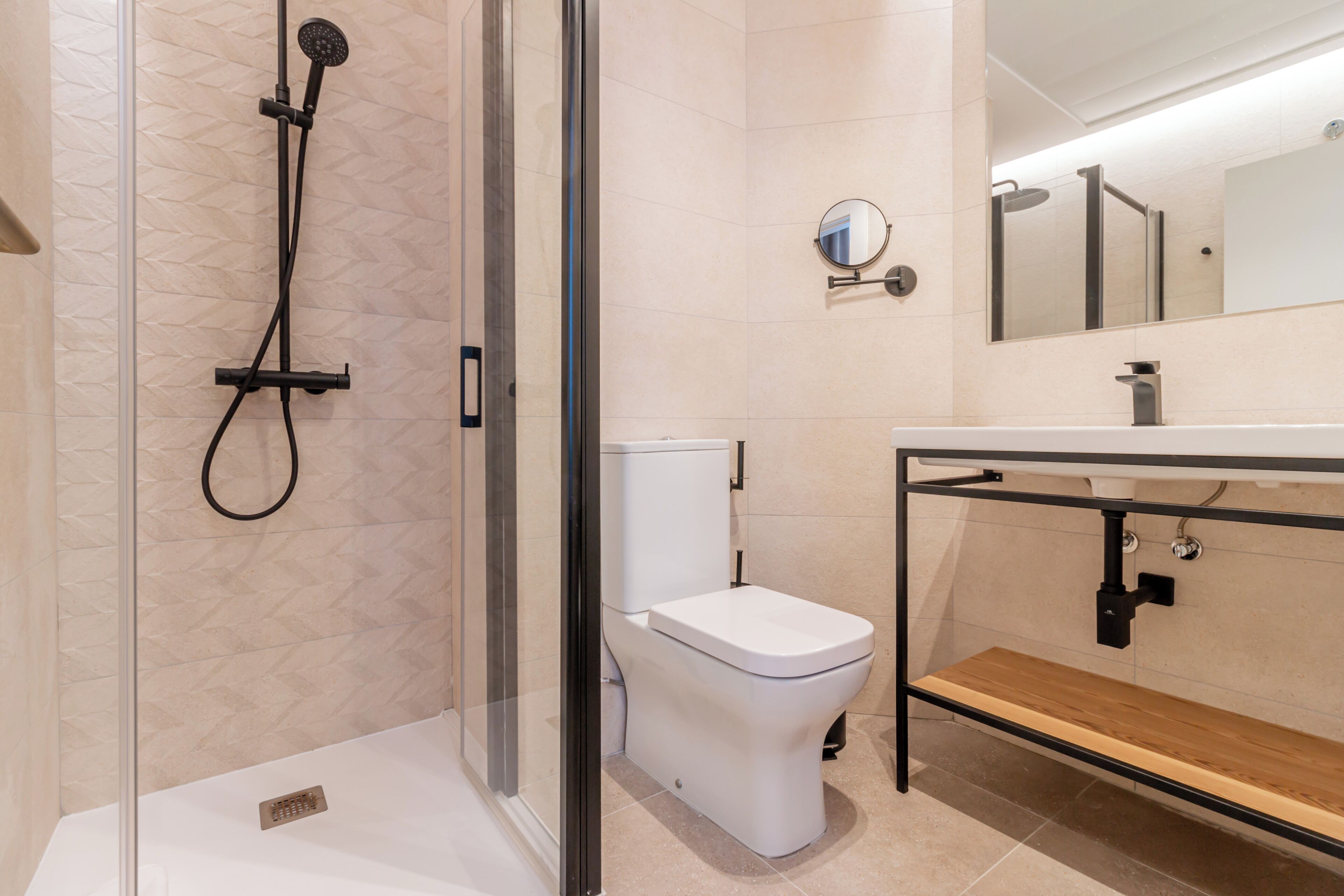 A modern bathroom with a glass-enclosed shower, a white toilet, and a wooden vanity with a mirror.