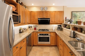 A kitchen with wooden cabinets, stainless steel appliances, granite countertops, and a built-in dishwasher. - Golf Season Deal, Summer Early Bird, Mountain Chalet, Steps To Village (Whistler)
