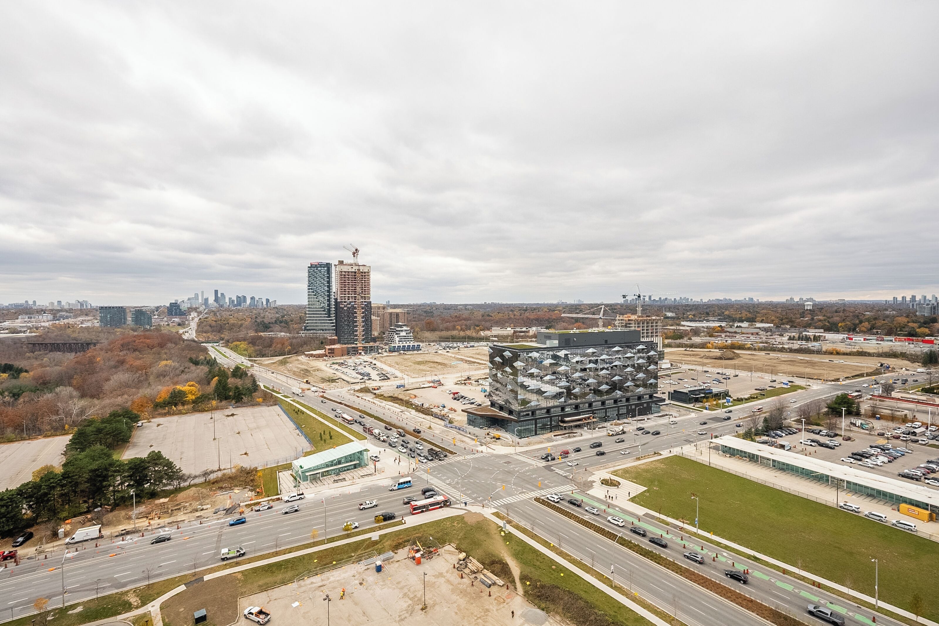 A cityscape with a modern building, a highway, and surrounding urban development.