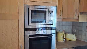 Une cuisine équipée d’un four à micro-ondes, d’un four et d’un grille-pain encastrés.