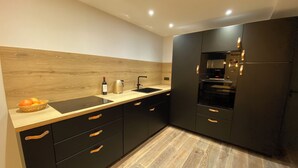 Eine moderne Küche mit dunklen Schränken, einer Holz Arbeitsplatte und einem eingebauten Backofen.