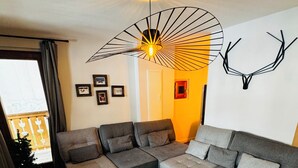 Ein modernes Wohnzimmer mit einem Ecksofa, einem Holztisch und einer außergewöhnlichen Deckenleuchte.