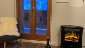 Ein Zimmer mit Holztür, Kamin, einer Weinflasche und zwei Gläsern auf einem Holztisch.