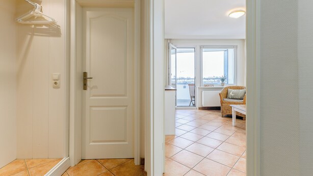 A hallway leading to a balcony with a wicker chair and a table, and a view of the city. - WindSpiel - House Ankerlicht - Westerland (Westerland)