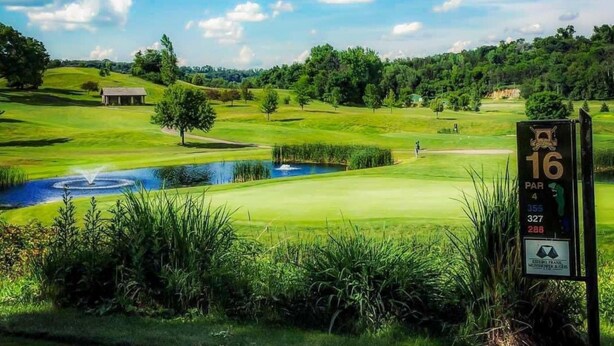 A golf course with a pond, a scorecard, and a building in the background. - The Vintage Inn - Hidden Gem! (Redwood Falls)