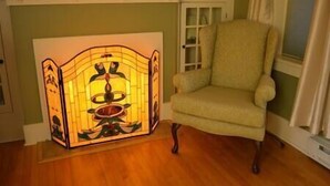 A room with a wooden floor, a chair, a wall-mounted shelf, and a decorative light fixture. - The Vintage Inn - Hidden Gem! (Redwood Falls)