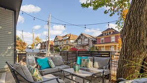 Une terrasse avec des meubles d’extérieur, un barbecue et une vue sur les maisons voisines.