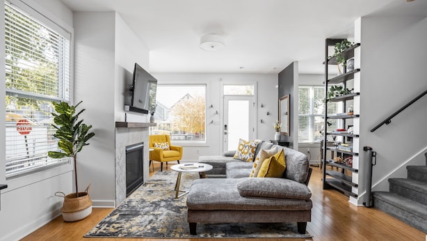 Un salon moderne avec un canapé gris, un fauteuil jaune et une cheminée.