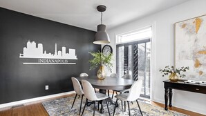 Un coin repas avec un mur noir, un décor mural représentant une vue sur la ville, une table ronde et des chaises.