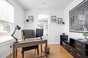 Un espace de bureau moderne comprenant un bureau, une chaise, un ordinateur et des étagères ornées de tableaux encadrés.