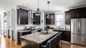 Une cuisine moderne avec des meubles en bois foncé, des appareils électroménagers en acier inoxydable et des plans de travail en granit.