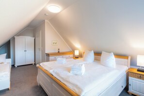 Relax in this cozy loft-style room with a large bed, bedside table, and wardrobe.