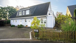 Ein zweistöckiges Haus mit Satteldach, einer Veranda und einem Holzzaun.