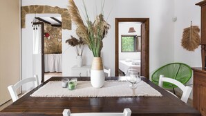 A dining area with a wooden table, white chairs, a vase with dried plants, and a green chair. - 4197 Villa Irma by Barbarhouse (Carovigno)