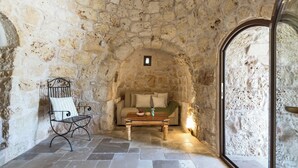 A stone-walled room with a sofa, a wooden coffee table, and a metal chair. - 4197 Villa Irma by Barbarhouse (Carovigno)