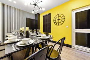 Enjoy meals in this stylish dining area with a long table, black chairs, and yellow cushions.