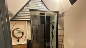 Een moderne badkamer met een douchecabine van glas, een houten wastafelmeubel en een vloer met een patroon.