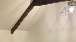 Een gezellige woonkamer met een zwarte bank, een ronde houten salontafel met twee potplanten, en een moderne hanglamp.