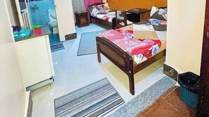 Habitación de hotel compacta con cama, escritorio, silla, kitchenette pequeña y baño.