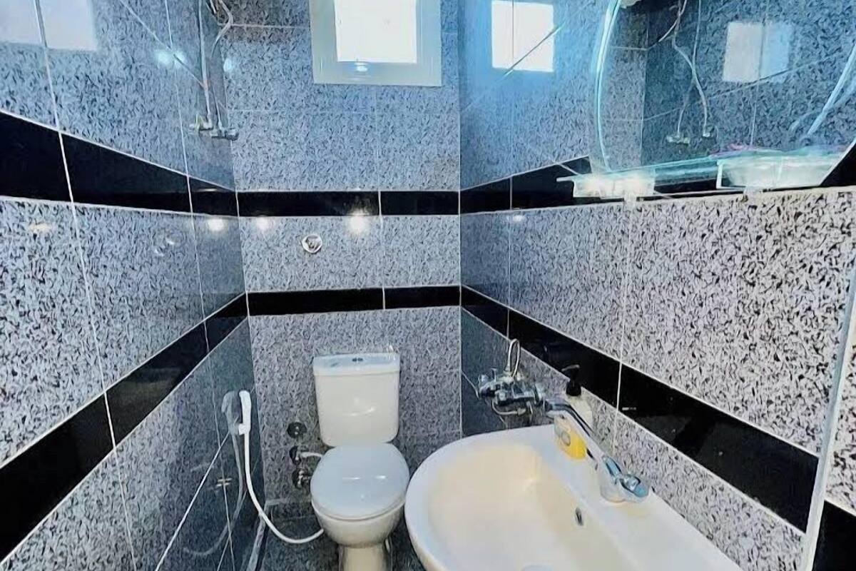 A bathroom with a sink, two toilets, and a shower.