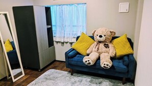 A room with a blue sofa, a teddy bear, and yellow pillows.
