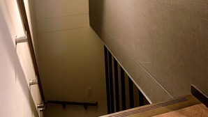 A narrow stairwell with a textured wall on the right and a plain wall on the left.