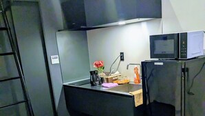 A compact kitchenette with a microwave, refrigerator, and a small sink area.