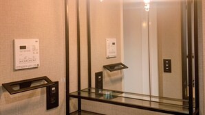 An elevator with a glass panel, control panel, and a mirror.