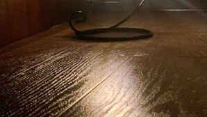 Une lanterne en métal, dotée d’un pied incurvé, posée sur une surface en bois.