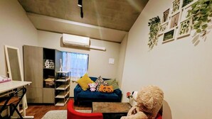 Un salon avec un canapé, un fauteuil rouge, un ours en peluche et un mur orné de tableaux.