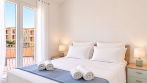 Una camera d'albergo con un letto, due comodini, una finestra con tende e vista su un balcone.