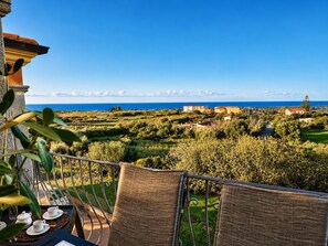 Ein Balkon mit Blick auf eine Küstenlandschaft, einschließlich Häuser und viel Grün.
