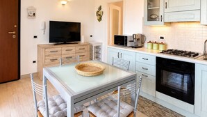 Una cucina compatta con zona pranzo, TV e fornello.