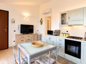 A compact kitchen with a dining area, a TV, and a stove.