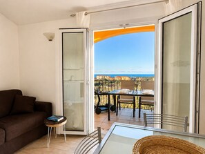 Ein Balkon mit Esstisch, einer Couch und einem kleinen Beistelltisch mit einem Buch.