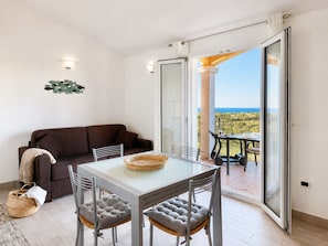 A balcony with a table and chairs, a sofa, and a view of the sea.