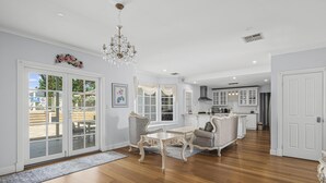 A spacious living room with a chandelier, a dining area, and a kitchen in the background. - Chateau On Vines ~ Aldinga - Welcome to Chateau On Vines (Aldinga)