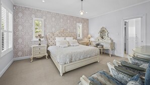 A bedroom with a large bed, a dresser, a vanity, and a mirror. - Chateau On Vines ~ Aldinga - Welcome to Chateau On Vines (Aldinga)