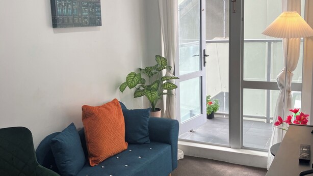 Un salon avec un canapé, un fauteuil, une lampe et une plante en pot.