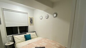 Une chambre à coucher comprenant un lit, une table de chevet, une fenêtre avec un store et des éléments décoratifs sur les murs.