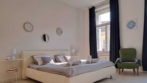 A neatly arranged bedroom with a bed, bedside tables, a chair, and a window with curtains.