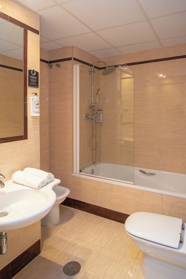 A modern bathroom with a sink, toilet, and a glass-enclosed shower area. - VTZ Hotel El Príncipe (Zaragoza)